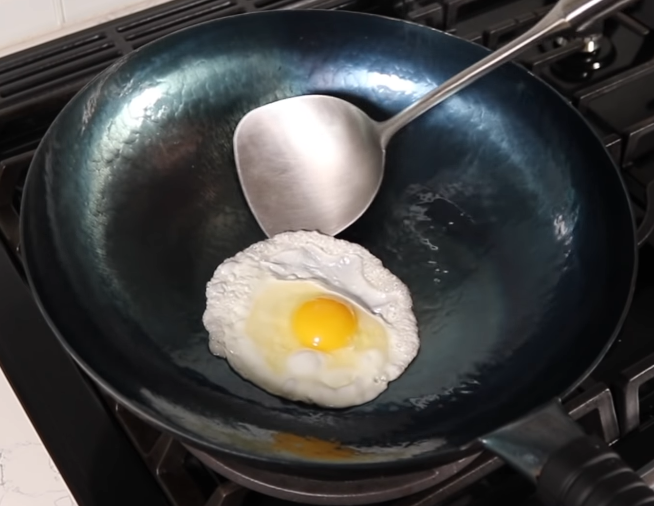 Wok on an electric stove frying an egg